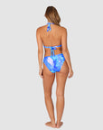 Woman wearing a blue and white tropical patterned bikini in style Kokomo showing regular coverage swim bottoms by brand Baku back view