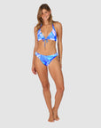 Woman wearing a blue and white tropical patterned bikini in style Kokomo showing regular coverage swim bottoms by brand Baku front view