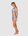 Woman wearing a blue and white tropical patterned bikini in style Kokomo showing regular coverage swim bottoms by brand Baku side view
