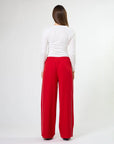 Woman wearing wide leg red pants with drawstrings and white stripes on sides by brand Stella & Gemma on a white background back view