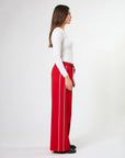 Woman wearing wide leg red pants with drawstrings and white stripes on sides by brand Stella & Gemma on a white background side view 