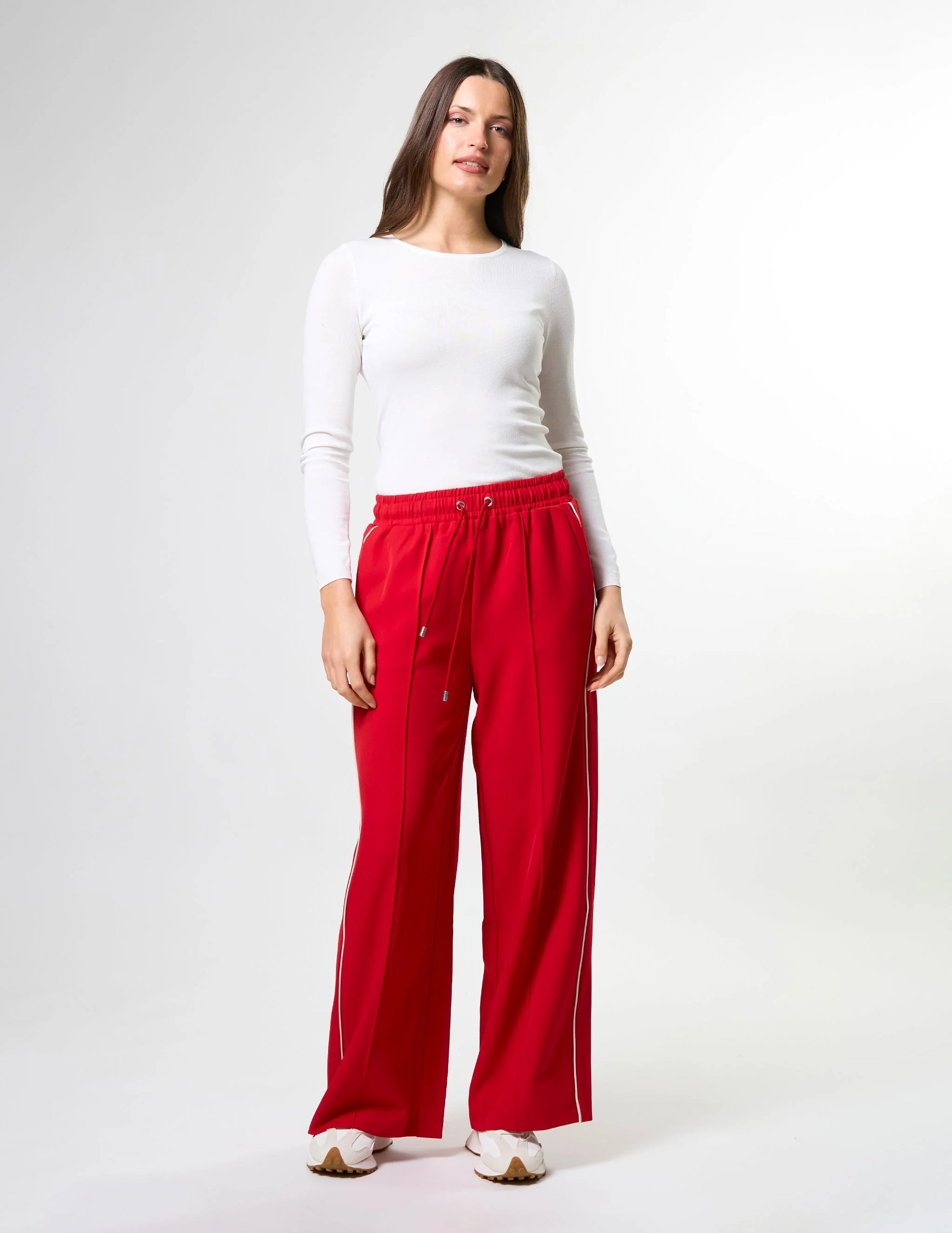 Woman wearing wide leg red pants with drawstrings and white stripes on sides by brand Stella & Gemma on a white background posed front view 