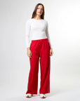 Woman wearing wide leg red pants with drawstrings and white stripes on sides by brand Stella & Gemma on a white background posed front view 